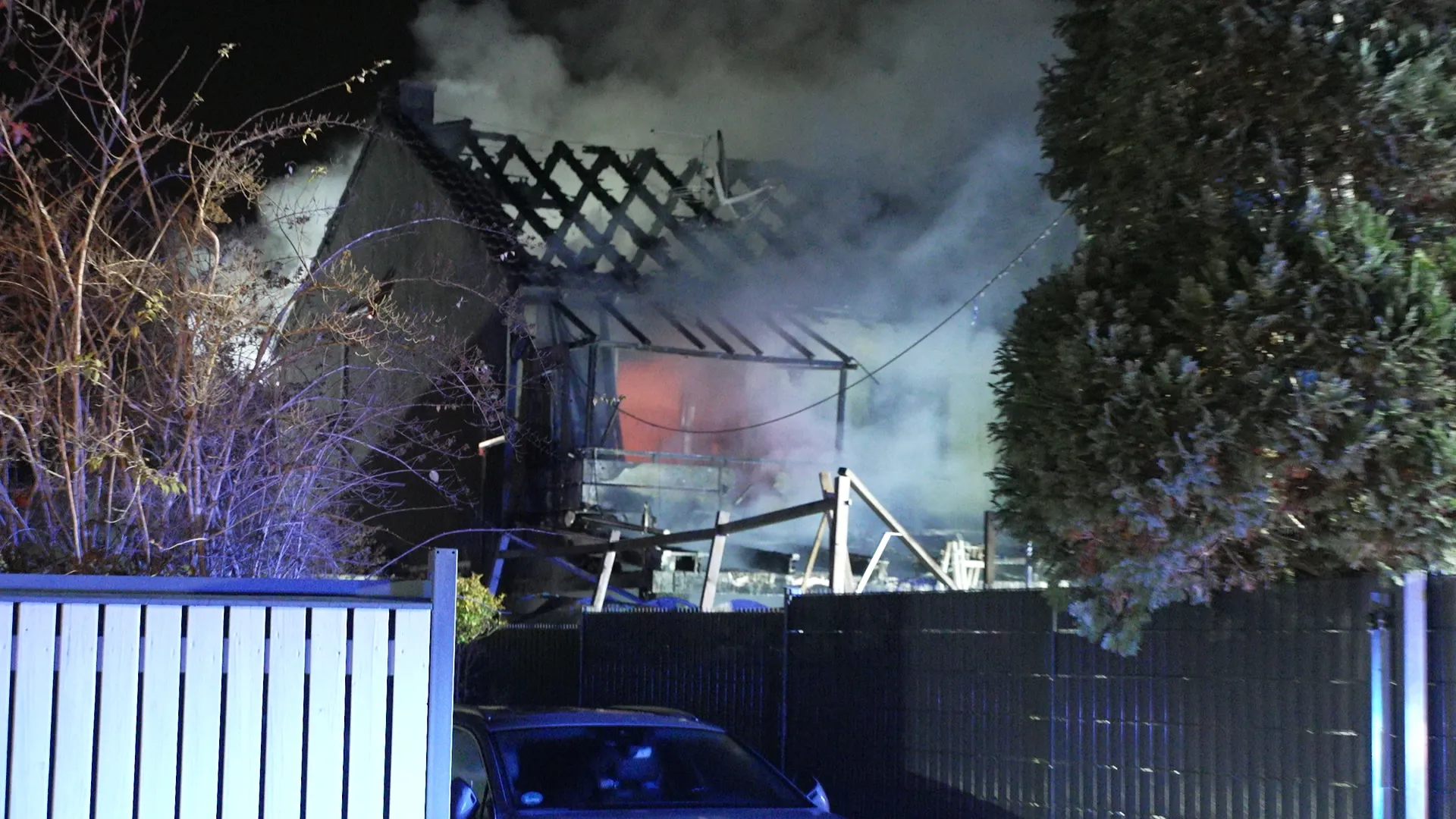 Ausgebranntes Reihenhaus nach Brand Reihenhaus Köln, starker Rauch und zerstörtes Dach in der Nacht.