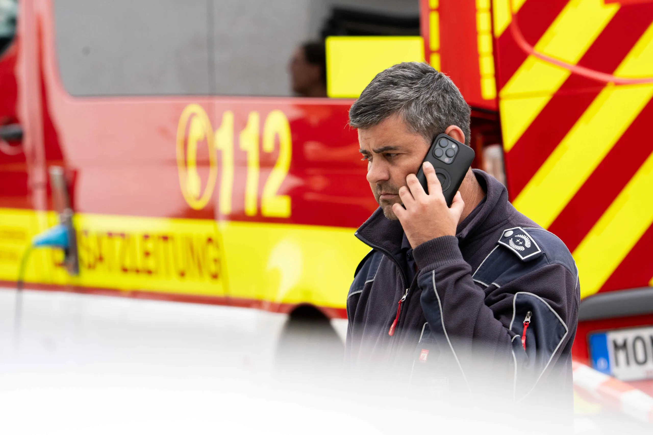 Feuerwehrleiter Philipp Krüger telefoniert vor einem Feuerwehrfahrzeug in Kalterherberg.