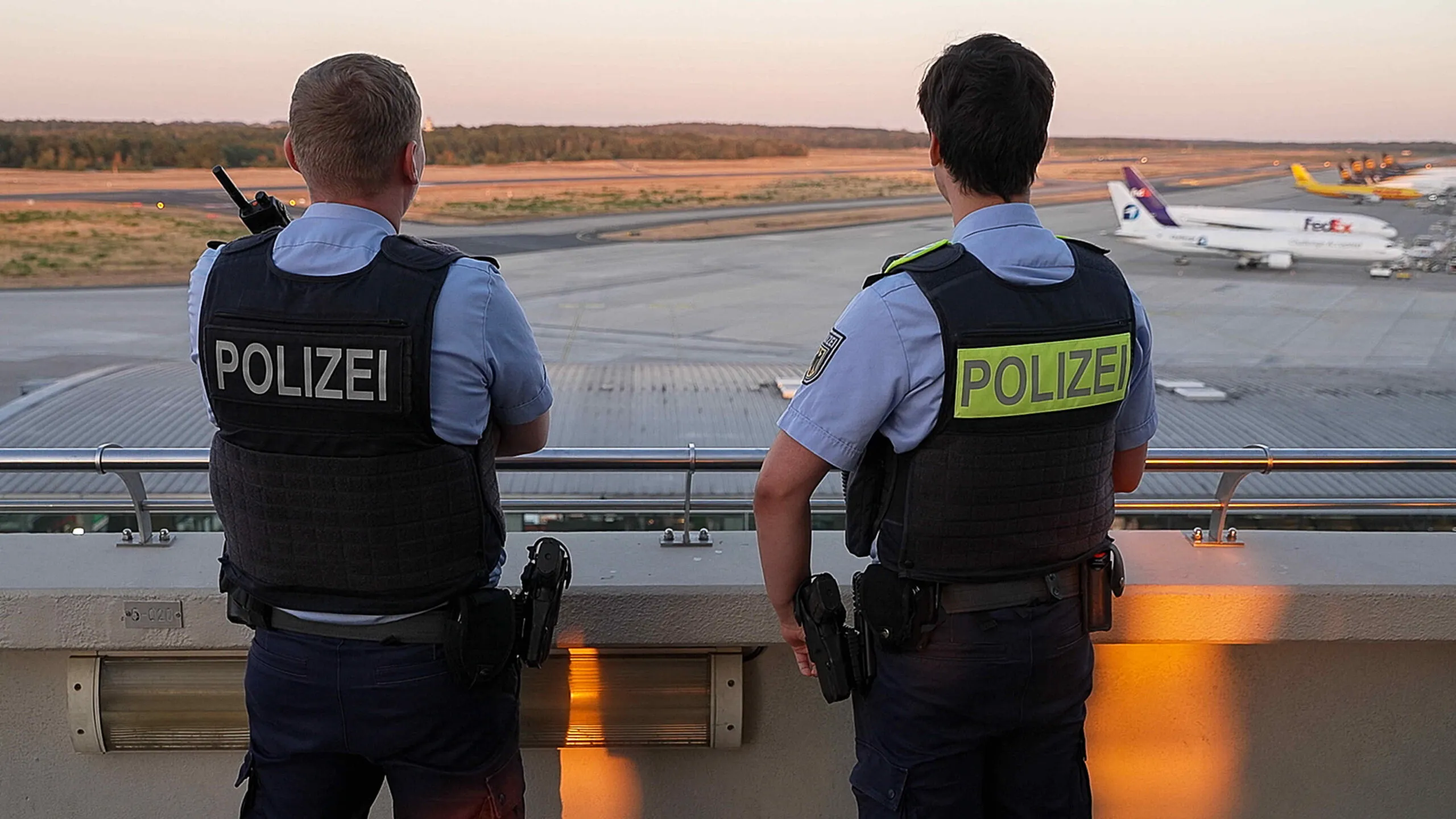 Zwei Polizeikräfte blicken auf das Flughafengelände am Flughafen Köln/Bonn.